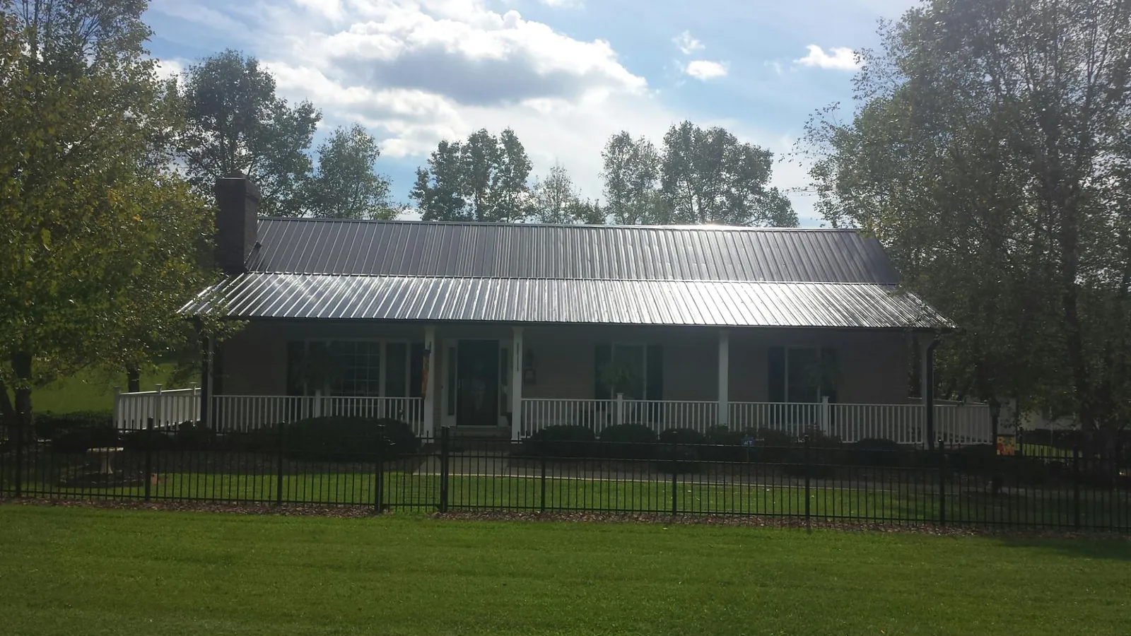 Gray metal roof on a brick ranch with a full width front porch — Gutter Guard Installation work by our crew in Federalsburg