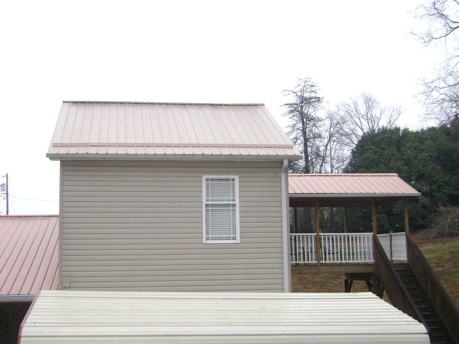 Tan metal roofs on a two story addition and attached porch, from a Roof Replacement job in Federalsburg